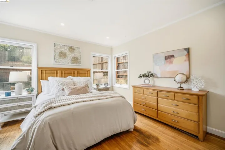 Bedroom featuring a light wood-finish headboard, multiple windows, wood-finish flooring, recessed lighting, and a light-toned wall color