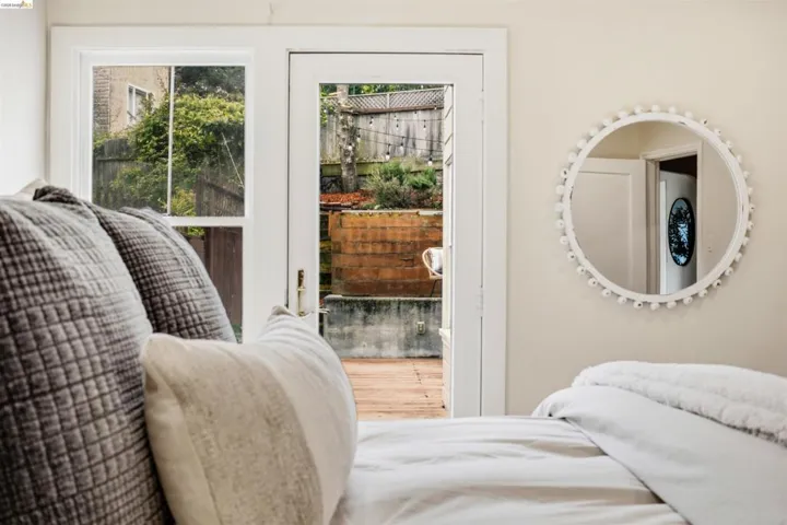 Patio door leading to an exterior wood-finish deck with tiered landscaping and a privacy fence