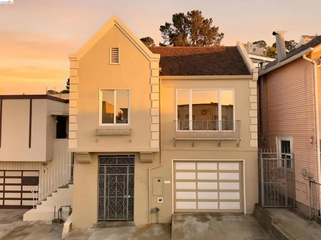 Stucco facade residence featuring a peaked gable, pronounced window trim, and a segmented garage door