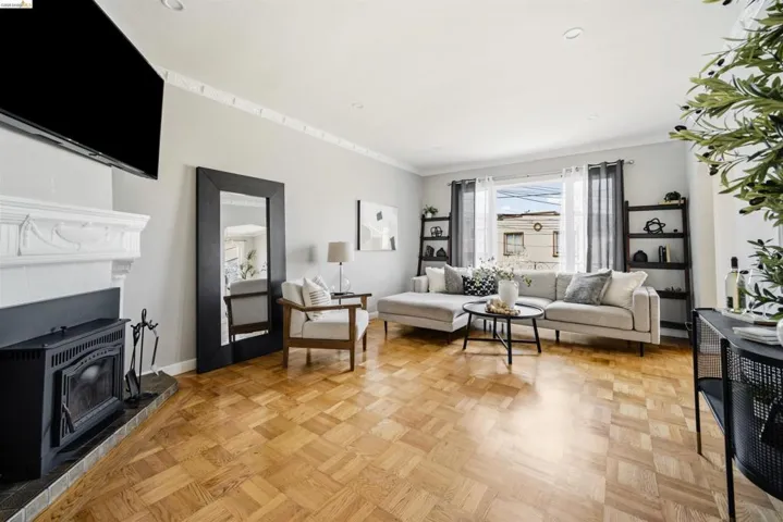 Living area featuring wood parquet flooring, a fireplace with a white mantel, recessed lighting, and a large window with privacy curtains