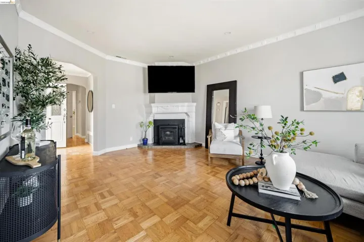 Living area featuring parquet wood flooring and a classic fireplace with a white mantel and black insert