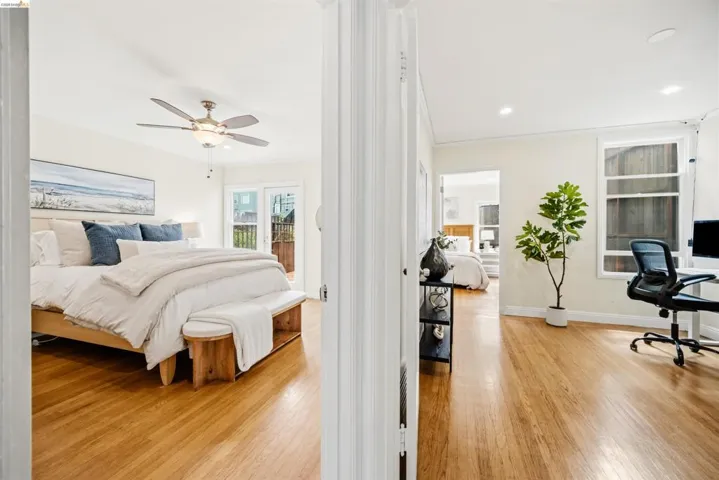 Light-filled interior featuring wood-finish flooring throughout, a bedroom with a ceiling fan, and French doors leading to an exterior area