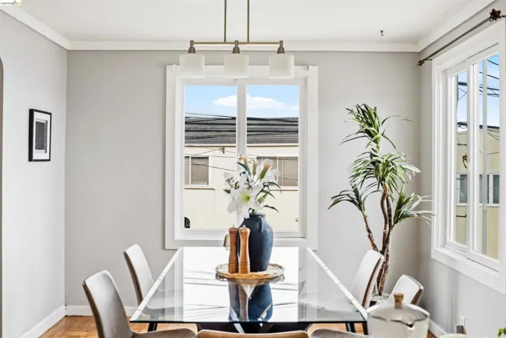 Dining area featuring a contemporary chandelier, two large windows, wood-finish flooring, and crown molding