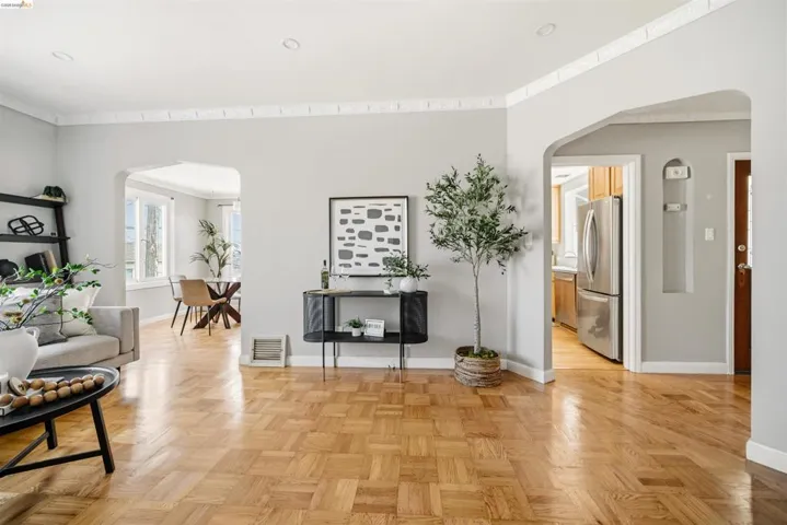 Hardwood parquet flooring extending through an open archway to a dining area with multiple windows