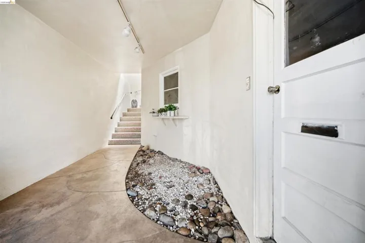Entryway featuring a concrete path, a decorative rock garden, and a white paneled door with a glass insert