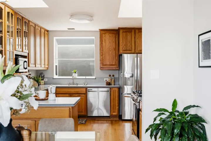 Kitchen featuring wood cabinetry, stainless steel appliances, a window above the sink, recessed lighting, and wood-finish flooring