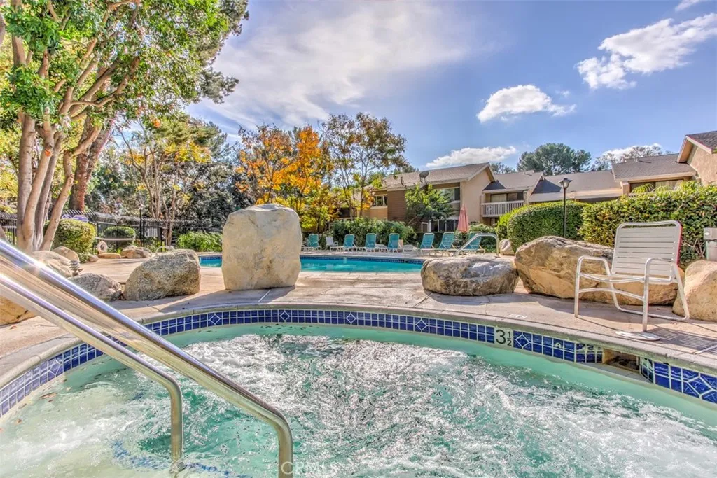 Community Pool and Spa – Pool and spa area framed by landscaping and nearby residential buildings.
