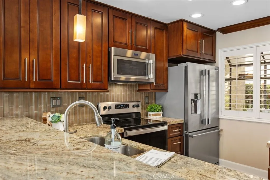 Kitchen – Efficient kitchen layout featuring wood cabinetry, tile flooring, and updated stainless steel appliances.
