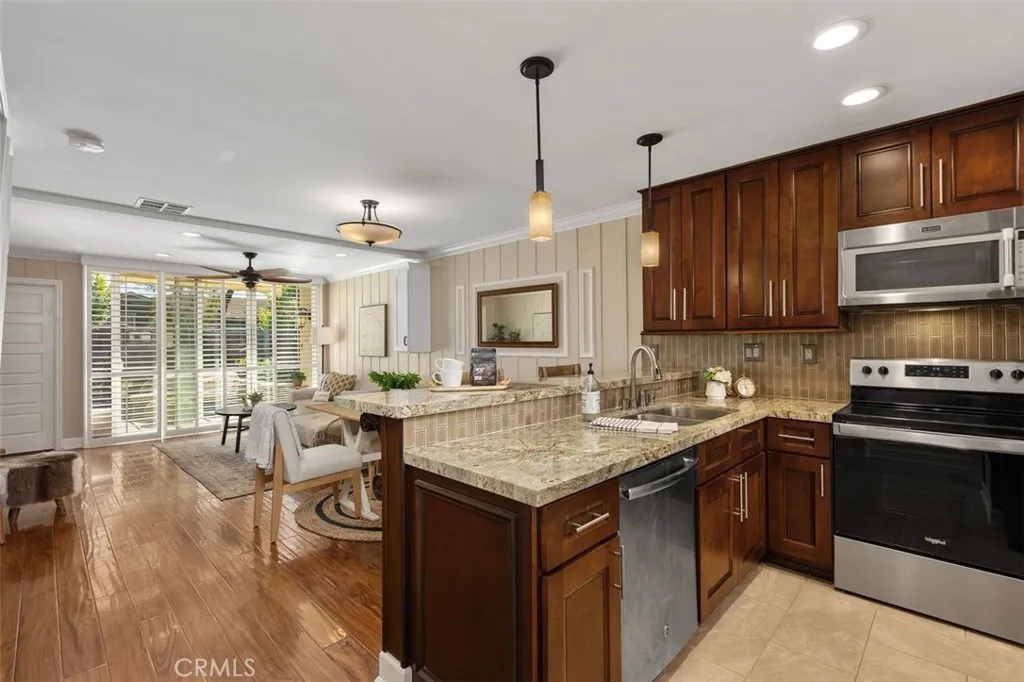 Kitchen – Updated kitchen with rich wood cabinetry, granite countertops, stainless steel appliances, and an open view into the adjoining living space.
