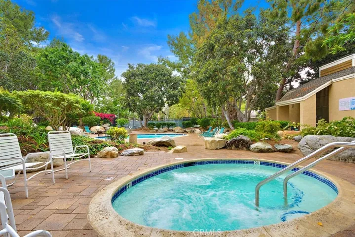 Community Pool – Curved pool area with adjacent spa, patio seating space, and landscaped surroundings.
