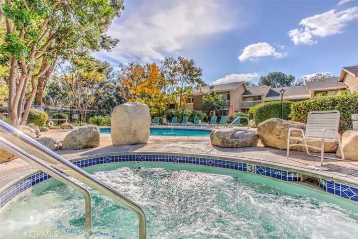 Community Pool and Spa – Pool and spa area framed by landscaping and nearby residential buildings.
