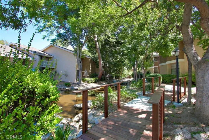 Community Grounds – Landscaped outdoor area with mature trees and wood foot bridges.
