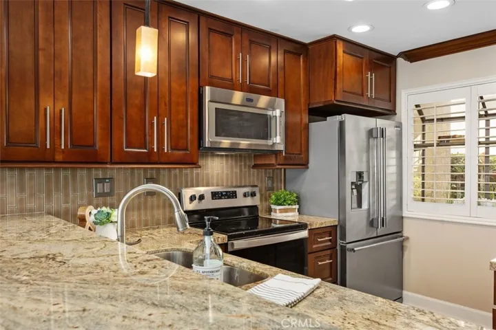 Kitchen – Efficient kitchen layout featuring wood cabinetry, tile flooring, and updated stainless steel appliances.
