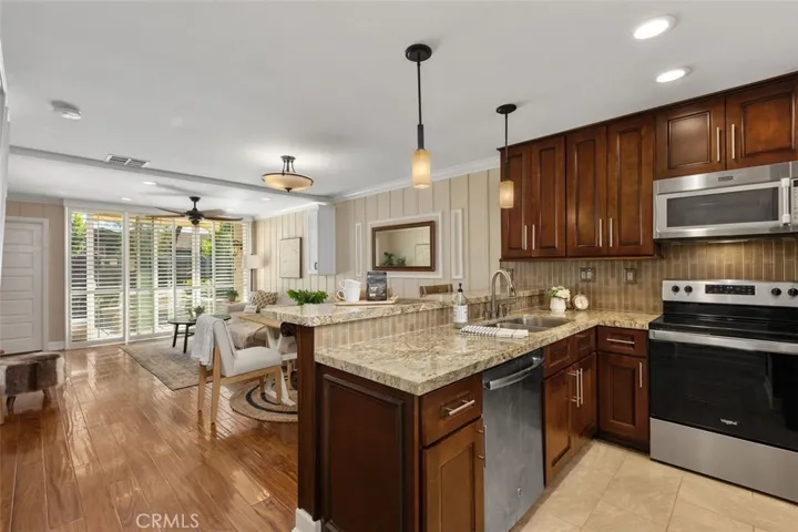 Kitchen – Updated kitchen with rich wood cabinetry, granite countertops, stainless steel appliances, and an open view into the adjoining living space.

