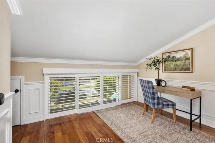 Office or Den – Light-filled bedroom with large window, neutral walls, and warm wood-look flooring.
