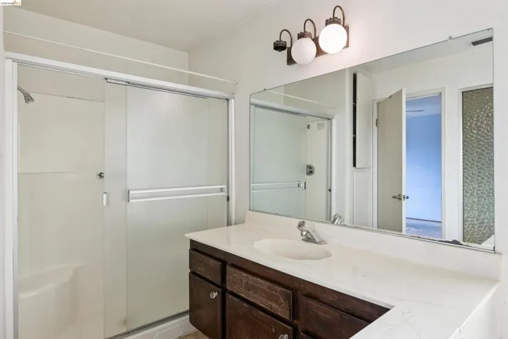 Bathroom featuring a shower stall with sliding glass doors, a built-in shower bench, and a mounted shower head