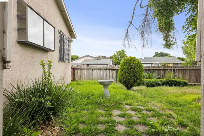 Expansive backyard featuring a privacy fence, mature shrubbery, and a stone garden pathway
