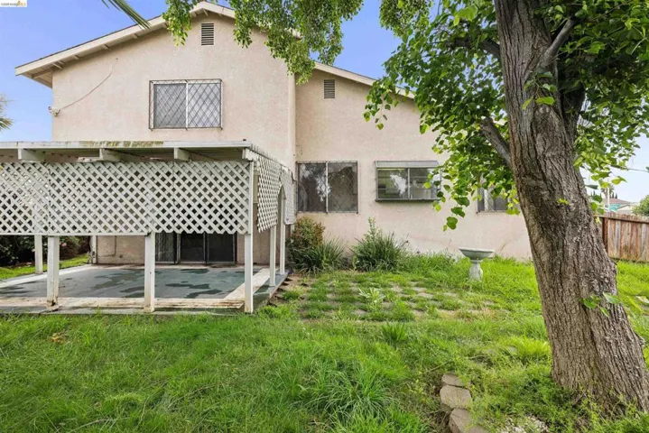 Rear exterior with a covered patio, featuring a lattice privacy screen and concrete flooring