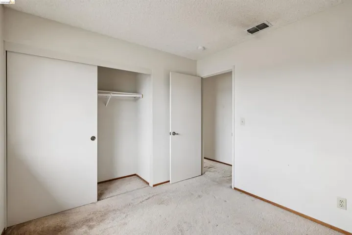 Carpeted room featuring a double-door sliding closet with an integrated hanging rod