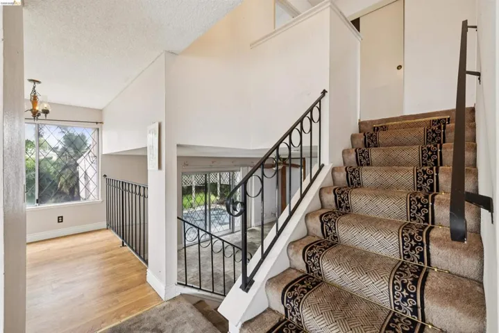 Carpeted staircase with an ornate runner and a wrought iron banister