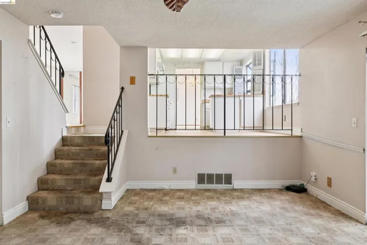 Open-concept living area with a visible staircase featuring wrought iron railings