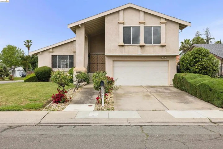 Two-story stucco residence featuring a two-car garage, a concrete driveway, and a front walkway