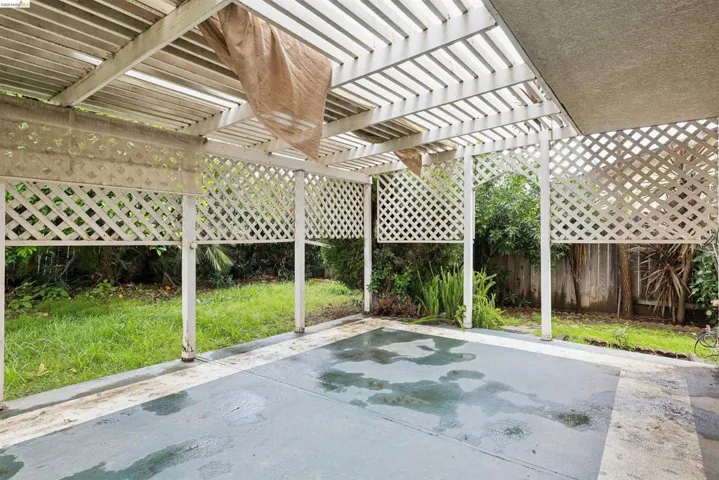 Covered patio area featuring a slatted pergola roof and lattice side panels