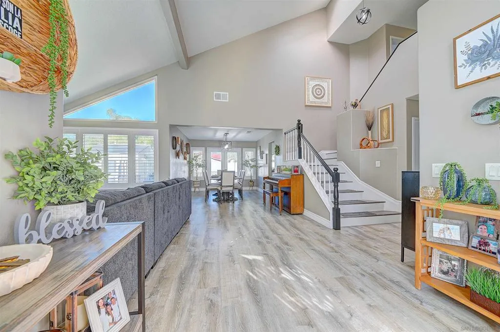 The moment you walk in, you know. Soaring vaulted ceilings, clerestory windows flooding the space with natural light, luxury vinyl plank flooring stretching all the way through, and a dramatic staircase anchoring the open floor plan — this entry sets the