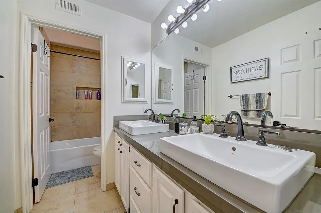 Dual vessel sinks, Hollywood vanity lighting, and a tub/shower combo — the shared hall bath is bright, clean, and ready for busy mornings with room for everyone.