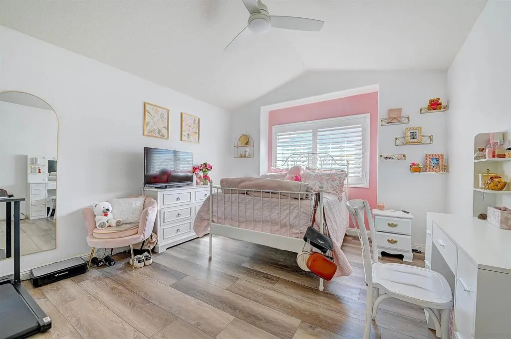 Bright and cheerful with vaulted ceilings, plantation shutters, luxury vinyl plank flooring, and a ceiling fan — a generous secondary bedroom that adapts to any lifestyle, from kids’ room to home office or guest suite.