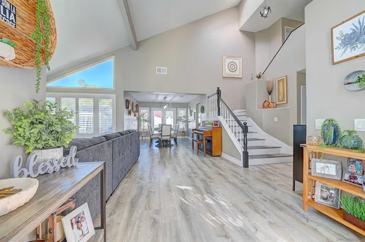 The moment you walk in, you know. Soaring vaulted ceilings, clerestory windows flooding the space with natural light, luxury vinyl plank flooring stretching all the way through, and a dramatic staircase anchoring the open floor plan — this entry sets the