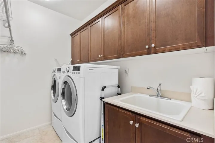 Indoor laundry room with sink and additional storage