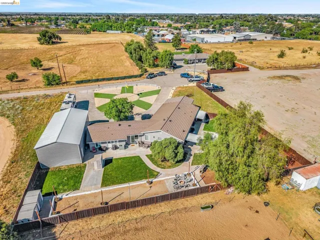 Aerial view showcasing a single-story residence with a metal roof and an expansive concrete patio