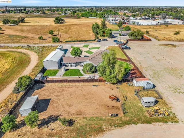 Expansive property featuring a single-story residence, a large metal outbuilding, fenced paddocks, and a manicured lawn area