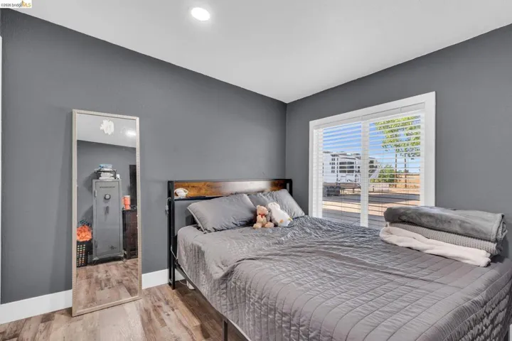 Room featuring wood-finish flooring, a contemporary ceiling light fixture, and a large sliding glass door with white blinds