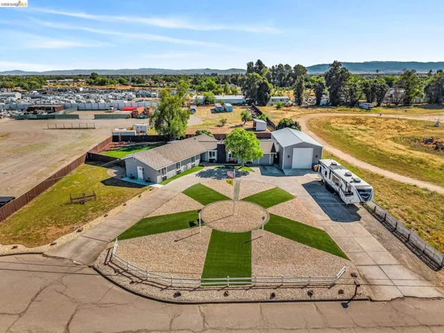 Expansive property featuring a contemporary single-story residence, a large detached metal structure, and a circular gravel drive with artificial turf accents