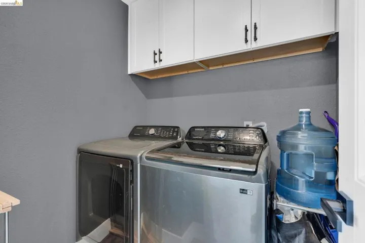 Laundry area featuring overhead white cabinetry with black hardware