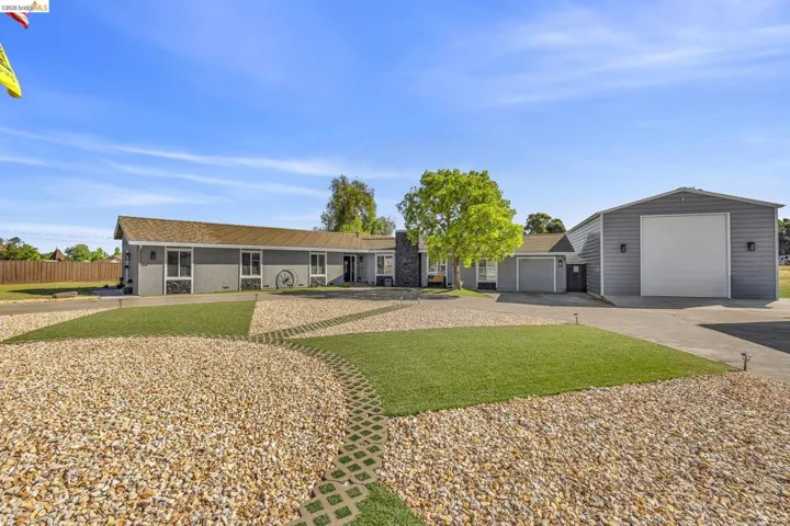 Ranch-style residence featuring a gray exterior and a large detached metal garage with a roll-up door