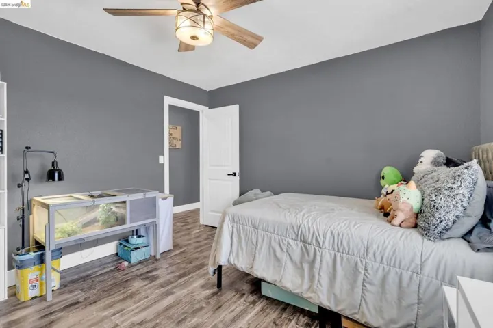Room with wood-finish flooring, a ceiling fan with integrated lighting, and a white paneled door