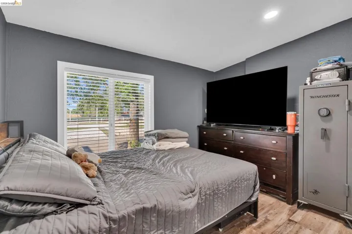 Bedroom featuring wood-finish flooring and a large window with blinds