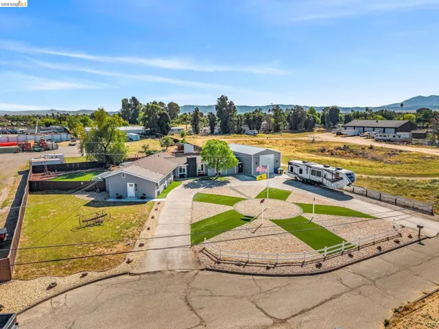 Expansive property featuring a paved driveway, a gray residential structure, and a large metal outbuilding