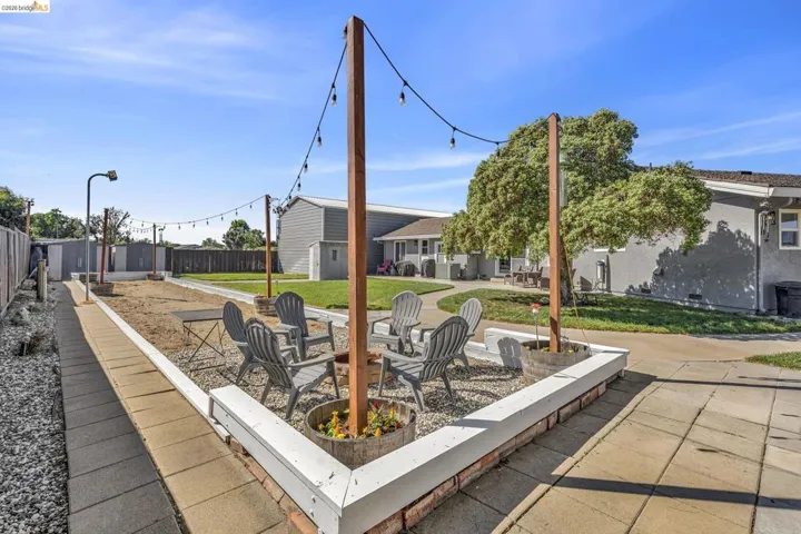 Outdoor patio featuring a gravel surface, string lights, and a low white perimeter wall with brick detailing