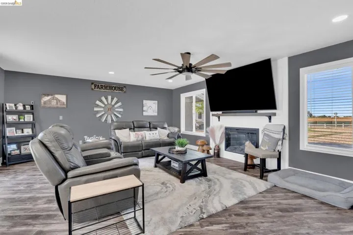 Spacious living area featuring wood-finish flooring and a ceiling fan