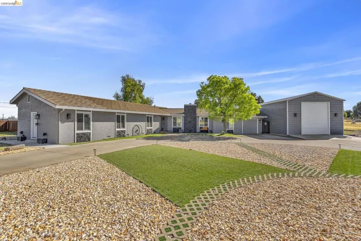Ranch-style exterior with a detached metal workshop featuring a roll-up door