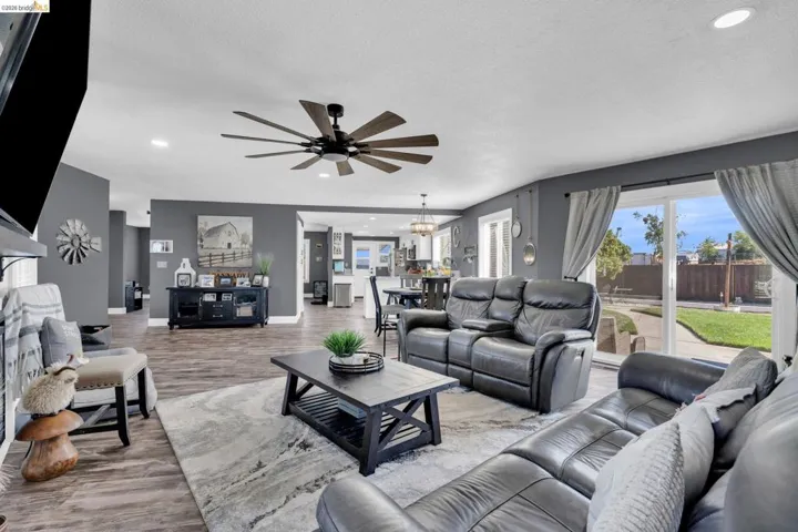 Spacious living area featuring wood-finish flooring, recessed lighting, and a multi-blade ceiling fan