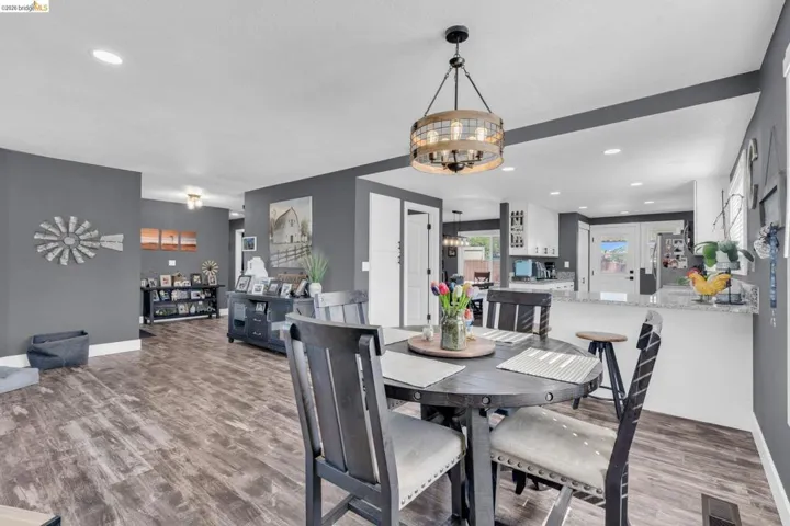 Open-concept dining area featuring wood-finish flooring, a contemporary chandelier, recessed lighting, and a neutral color palette