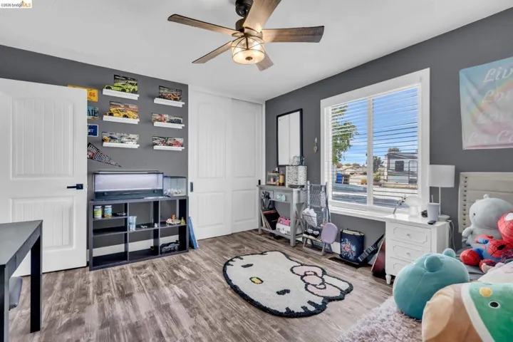 Interior room featuring wood-finish flooring and a ceiling fan with integrated lighting