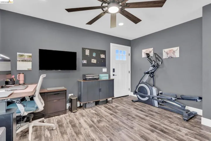 Versatile room featuring wood-finish flooring and a ceiling fan with integrated lighting