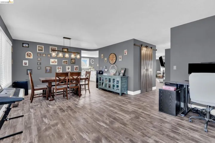Open-concept living space featuring wood-finish flooring, dark gray wall paint, and white trim