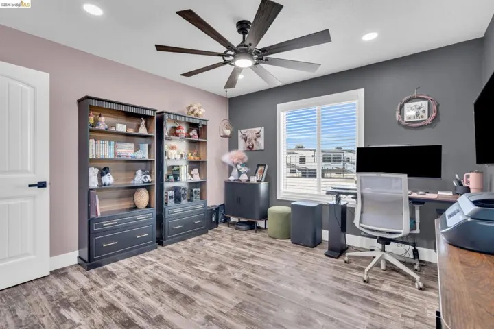 Versatile room with wood-finish flooring and a contemporary ceiling fan